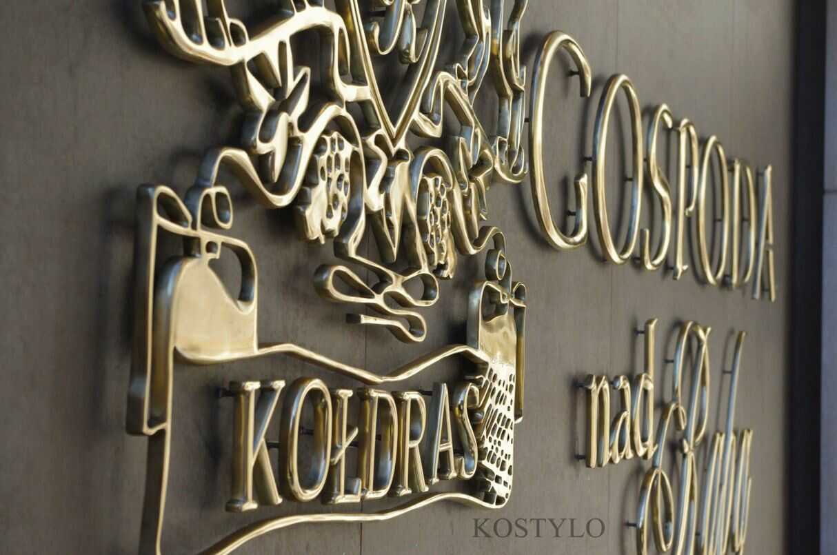 close-up of high-quality, unique solid brass relief in the shape of an openwork with inscriptions and logos, polished to high gloss authored Kostylo atelier