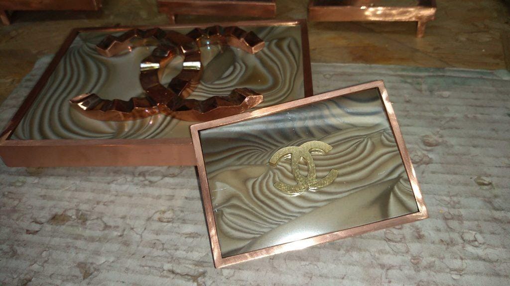 how_we_create_luxury_belt_buckle_fitting_the_striped_flint_into_buckle_hand_crafted_by_kostylo_atelier copper-plated belt buckles along with carefully fitted unique and rare striped flint stones and the coco chanel logo are handcrafted by the Kostylo atelier before being gilded