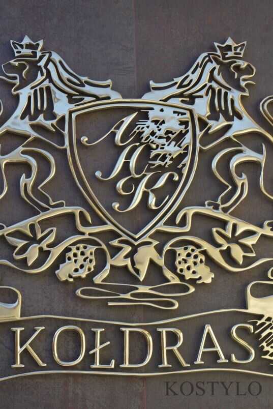 openwork relief in the shape of the company logo made of polished brass on stone brown background, made to order, handicraft by Kostylo atelier