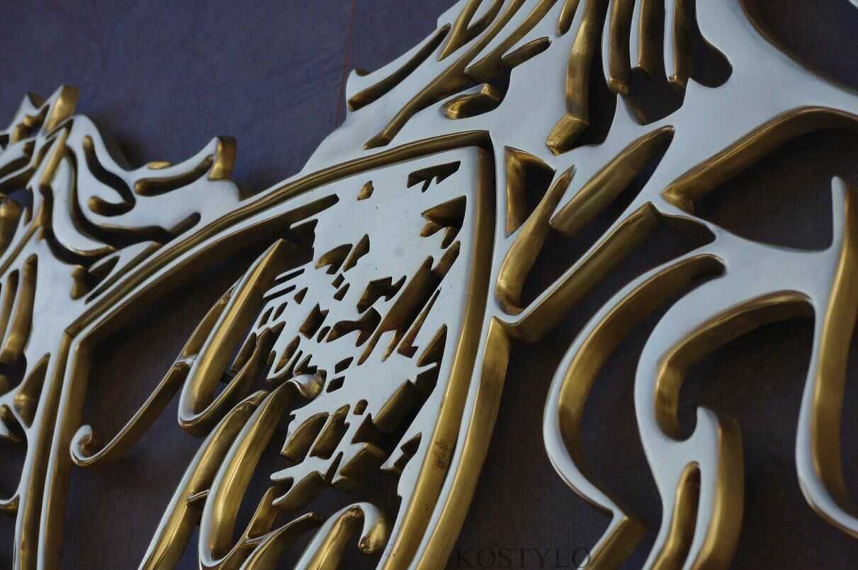 closeup of openwork brass polished company coat of arms logo looking artistic handmade by Kostylo atelier