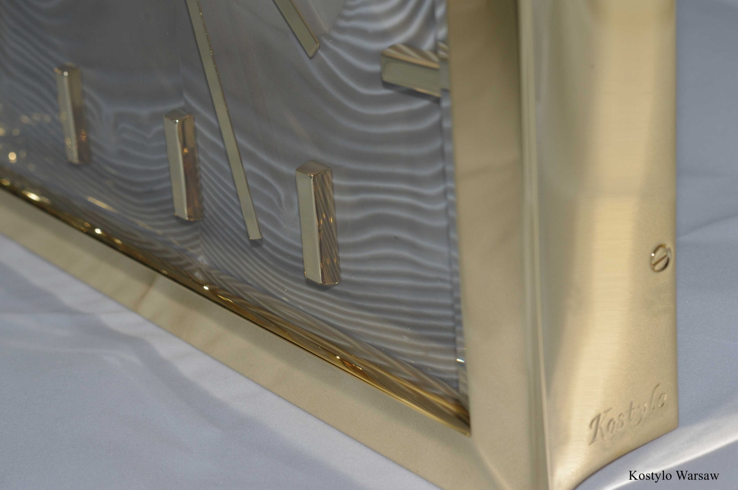 Detail of the side of the luxury gold-plated wall clock with gilded 23-karat gold indices and hands, featuring a dial made from unique striped flint, the stone of optimism handcrafted by atelier kostylo